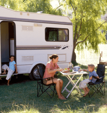 A woman relaxing in front of an RV with her kids